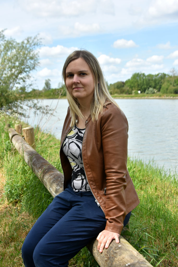 Emeline DUBAELE assise au bord de l'eau