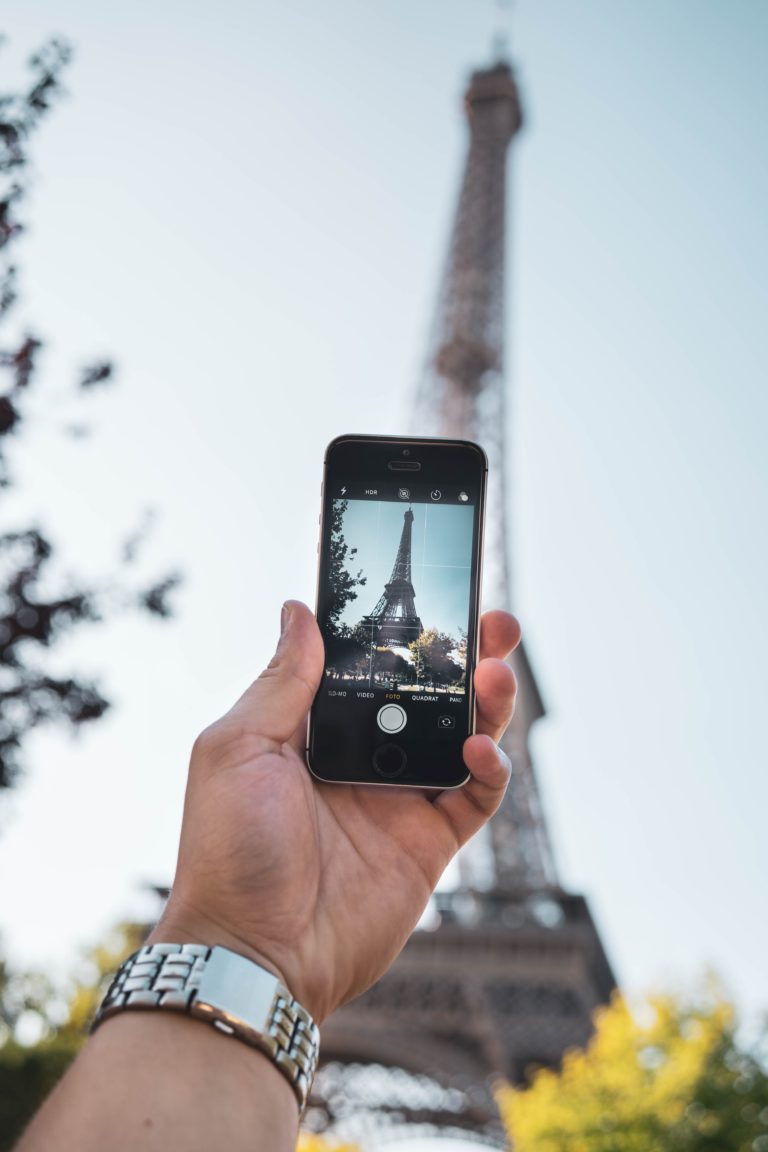 Personne prenant en photo la tour Eiffel à l'aide de son smartphone